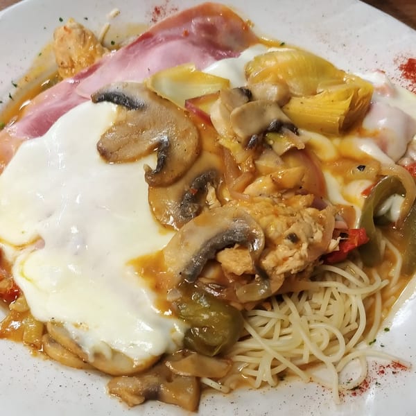 Mama Nina's Italian pasta dish with chicken, mushrooms, ham, melted cheese, and vegetables.