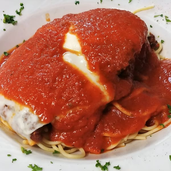 Mama Nina's spaghetti with meatballs, melted mozzarella, and rich red marinara sauce, garnished with parsley.